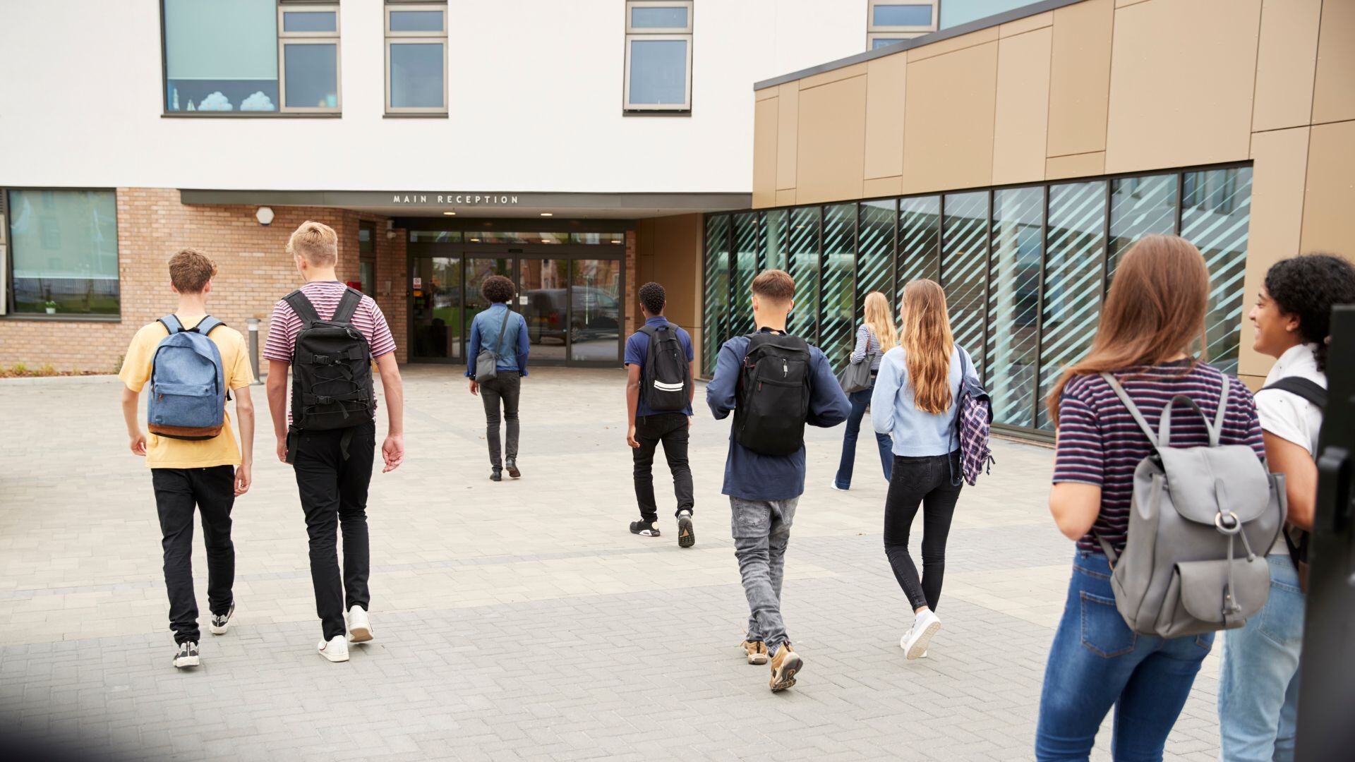 The front of a highschool with students walking in